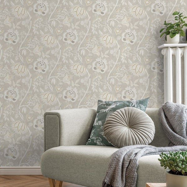 Wohnzimmer mit floraler Tapete, Sofa, Kissen, Decke und Zimmerpflanzen.