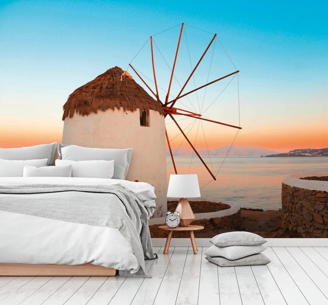 Fototapete mit Windmühle am Meer bei Sonnenuntergang in einem hellen Schlafzimmer mit weißem Holzboden und modernem Bett.