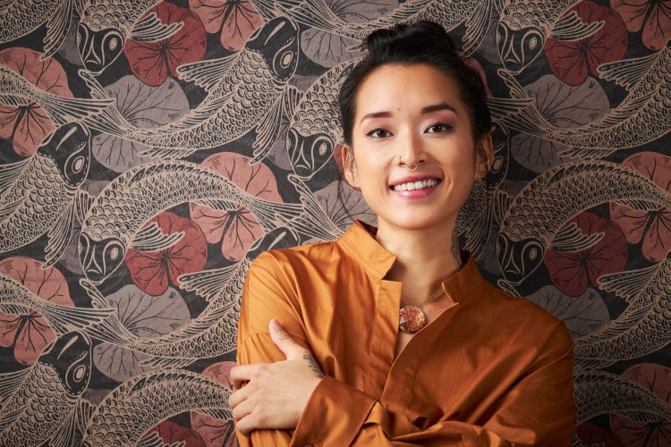 Frau vor Tapete mit Fisch- und Seerosenmuster