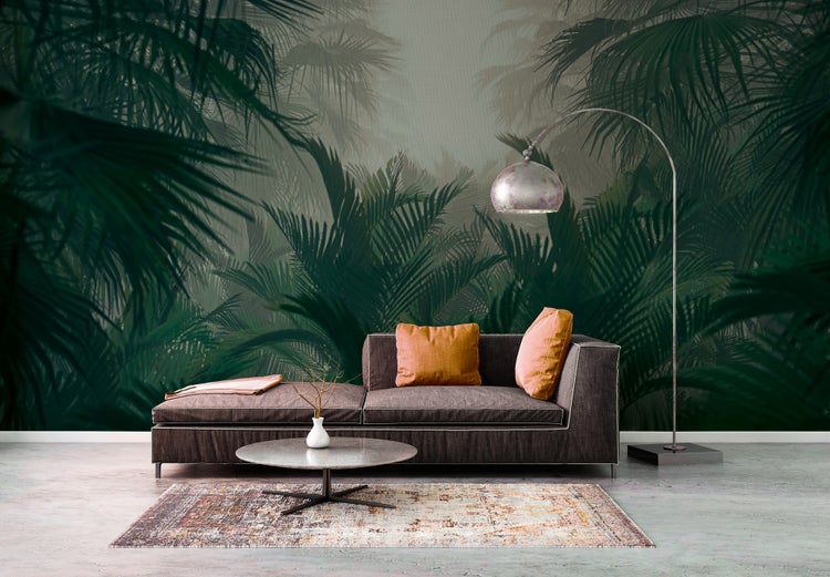 Fototapete mit dunklen Palmenblättern in einem modernen Wohnzimmer mit braunem Sofa, Bogenlampe und gemustertem Teppich.