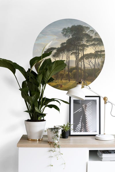 Dekoratives Interieur mit Wandtattoo, Zimmerpflanzen, Lampe und gerahmtem Bild auf einem Tisch