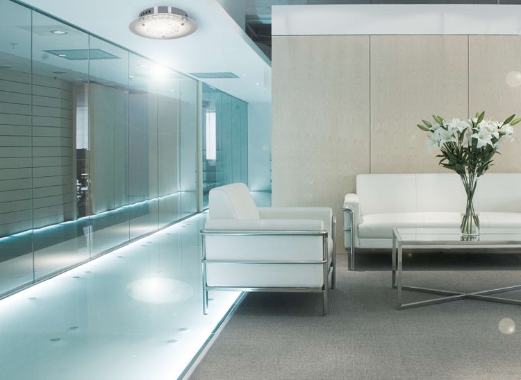 Lounge-Bereich mit weißen Sofas, Couchtisch und Deckenleuchte in einem modernen Bürogebäude