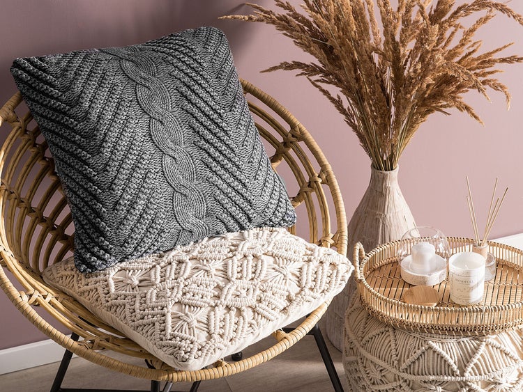 Dekoratives Wohnambiente mit Rattansessel, Zierkissen, Trockenblumen und Kerzen