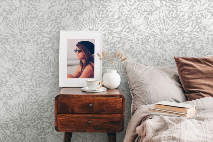 Szene mit gemusterten Tapeten, Nachttisch, Bett und dekorativen Elementen für das Schlafzimmer