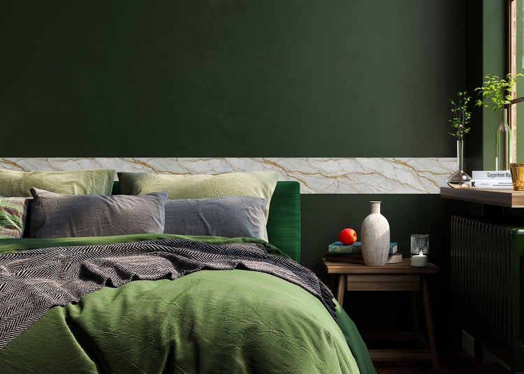 Tapetenbordüre mit Marmormuster und Goldadern auf einer dunkelgrünen Wand in einem Schlafzimmer mit Bett und Nachttisch.