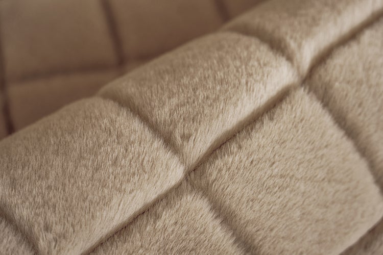 Nahaufnahme eines weichen, beigen Plüschstoffs mit quadratischem Steppmuster.