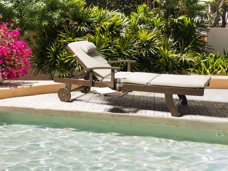 Holzliege mit Auflage, Beistelltisch und Rädern neben Pool im Garten