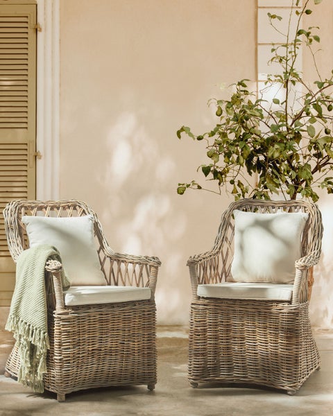 Zwei Rattansessel mit Kissen und Decke im Außenbereich