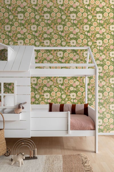 Tapete mit Blumenmuster im Kinderzimmer an der Wand hinter einem weißen Hausbett.