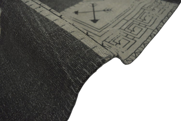 Grauer gewebter Teppich mit Pfeilmuster und Ziernaht an der umgeschlagenen Kante.