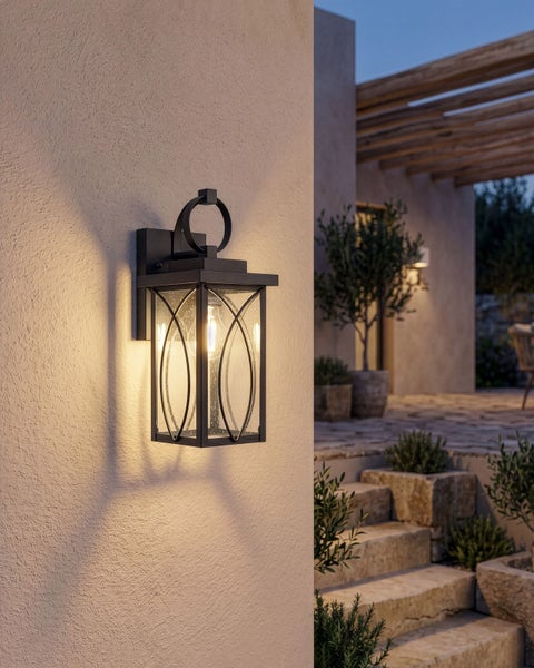 Schwarze Außenwandlaterne mit Blasenglas an strukturierter Wand, Terrasse mit Steintreppen und Pflanzen in der Dämmerung.
