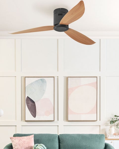 Moderner Deckenventilator mit drei Holzflügeln und schwarzem Gehäuse in einem hellen Wohnzimmer mit Wandpaneelen und abstrakter Kunst.