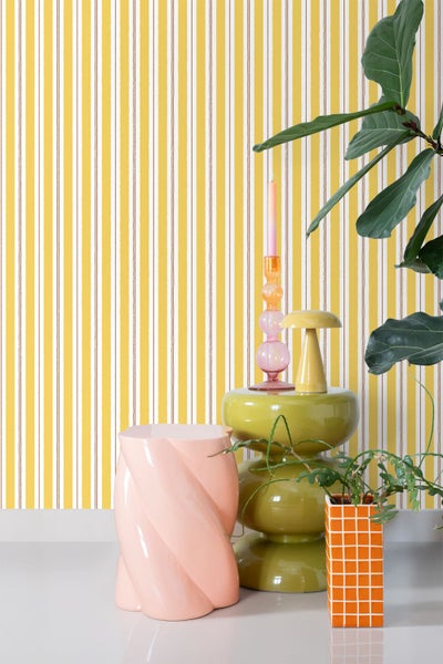 Zimmeransicht mit gestreifter Tapete, Beistelltisch, Kerzenhalter, Hocker und Topfpflanze.