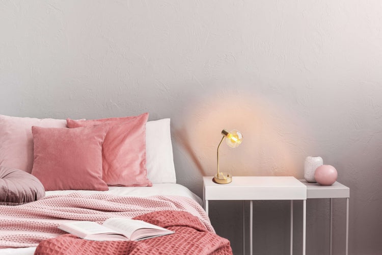 Schlafzimmer-Szene mit Bett, Nachttisch, Lampe und Dekorationsartikeln für eine gemütliche Atmosphäre