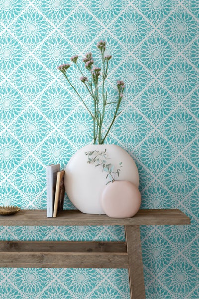 Dekorative Wand mit floral gemusterter Tapete, einem Holztisch, Vasen und Büchern