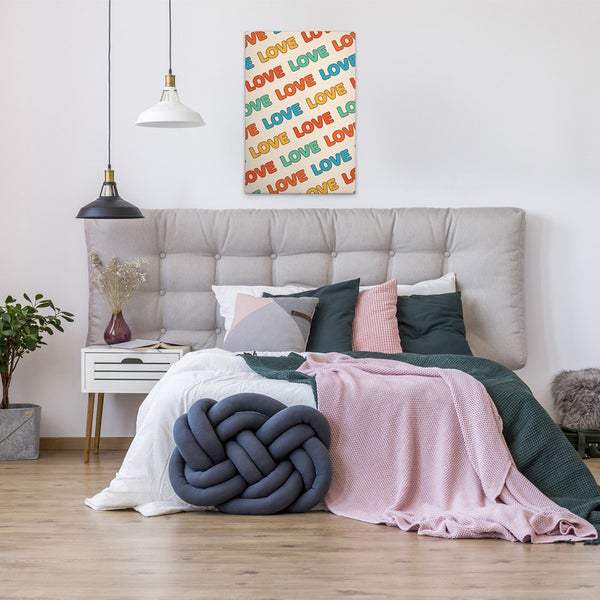 Dekoriertes Schlafzimmer mit Doppelbett, Nachttisch und Wandbild mit dem Schriftzug Liebe