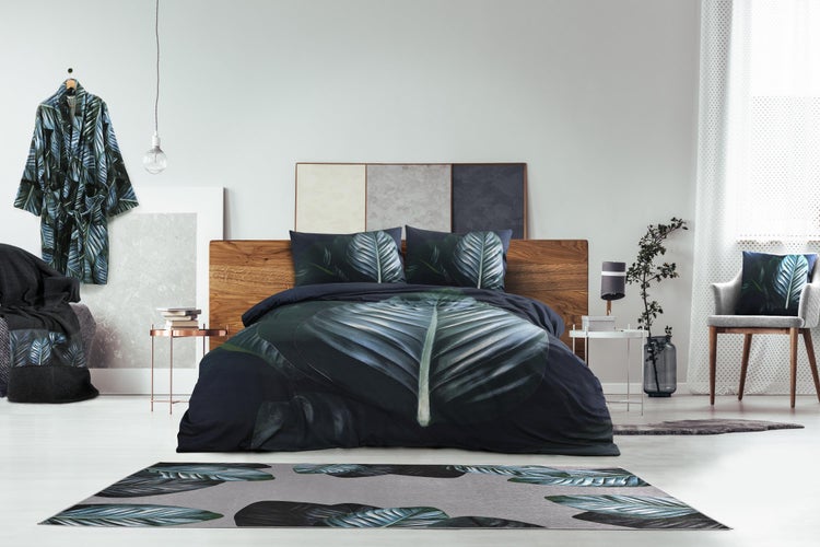 Modernes, helles Schlafzimmer mit Holzbett, dunkler Bettwäsche mit Blattmuster und passendem Teppich, organisiert und geräumig.