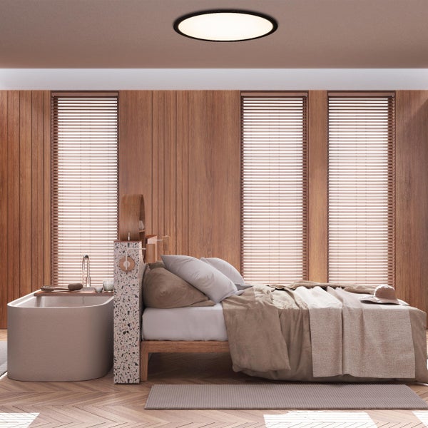 Helles Schlafzimmer mit Holzwänden, Badewanne und Jalousien