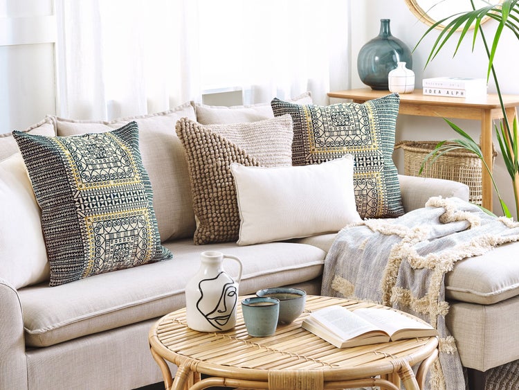 Wohnzimmer mit Sofa, Kissen und Tischdekoration für eine gemütliche Atmosphäre.