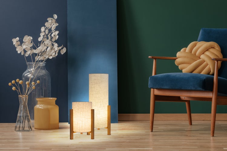 Dekorative Szene mit Stuhl, Kissen, Vasen und Lampen vor blauem und grünem Hintergrund.