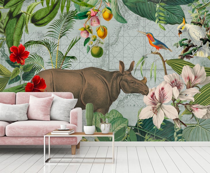 Wohnzimmer mit tropischer Fototapete mit Nashorn, exotischen Vögeln und Blüten, davor ein rosa Sofa und ein weißer Holzboden.