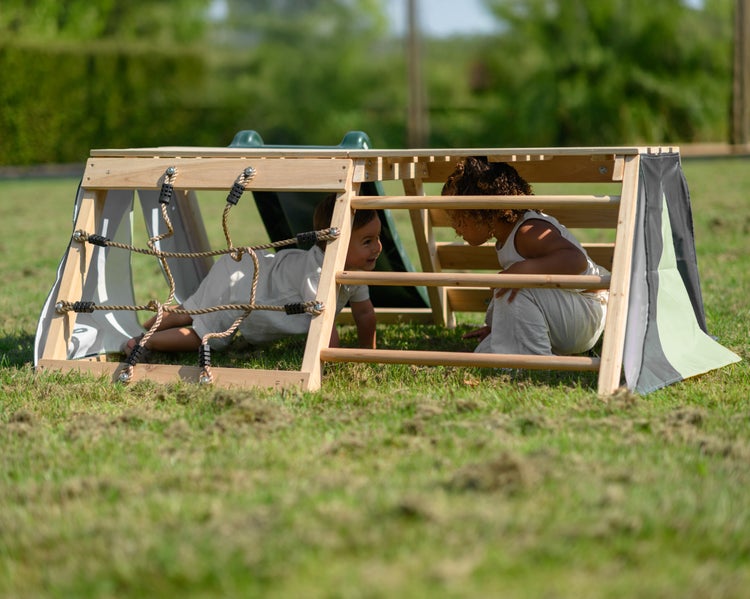 Zwei Kinder spielen auf einem hölzernen Klettergerüst im Garten