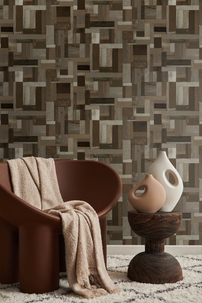 Raumansicht mit Holzblocktapete, Sessel, Decke, Beistelltisch und Vasen.