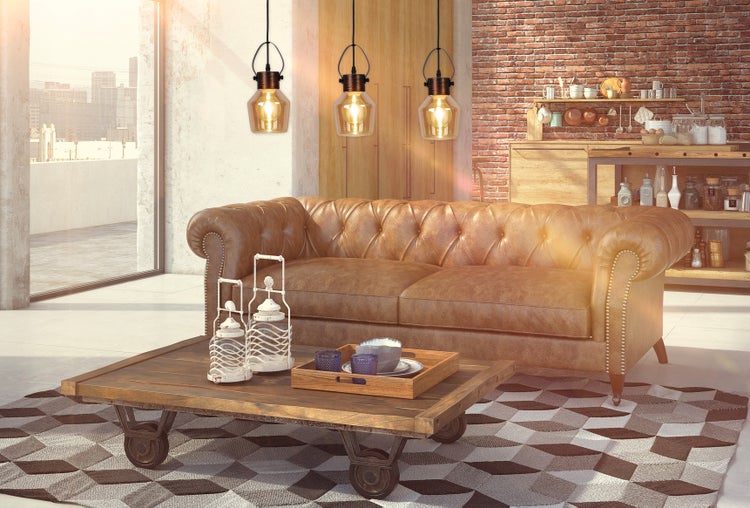 Wohnzimmer mit dekorativen Wanduhren, Lampe, Koffer auf Tisch und Stuhl vor einer Ziegelwand