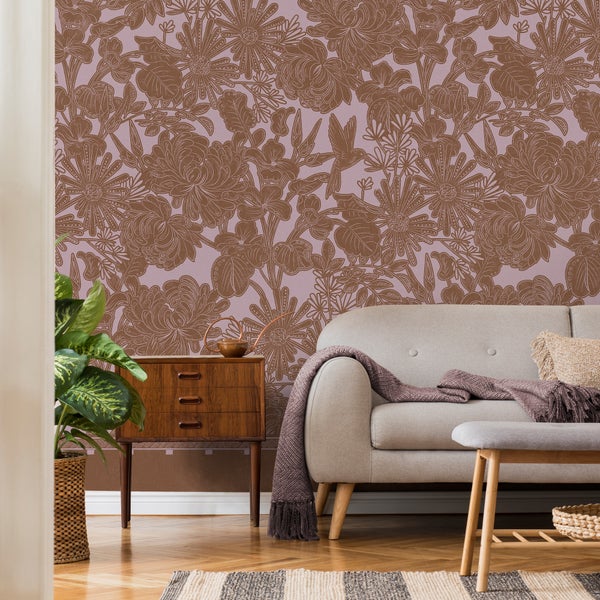 Wohnzimmer mit floral gemusterter Vliestapete, einem hellgrauen Sofa, einer Holzkommode und einer Zimmerpflanze im gemütlichen Retro-Stil.