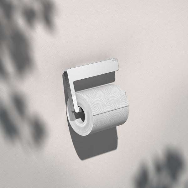 Wandmontierter Keuco Toilettenpapierhalter aus Metall mit Toilettenpapierrolle an der Wand.