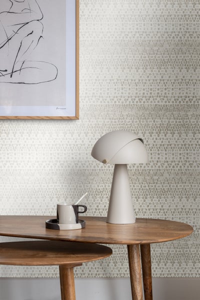 Nahaufnahme eines Raumes mit gemusterter Tapete, einem Tisch, einer Lampe und einem Bild