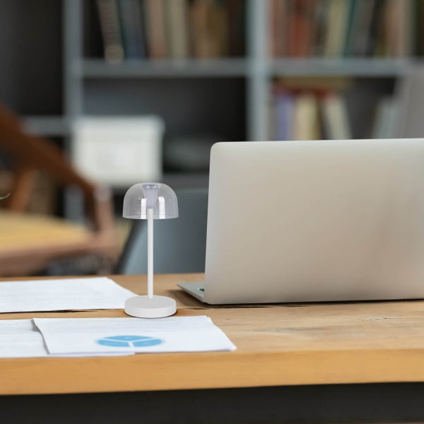 Tischleuchte auf einem Schreibtisch neben einem Laptop und Dokumenten