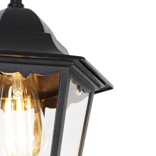 Detailansicht einer schwarzen Außenlaterne aus Metall mit Glaseinsätzen und leuchtendem Filament-Leuchtmittel.