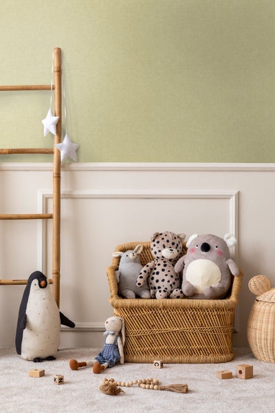 Hell olivgrüne strukturierte Tapete in einem hellen Schlafzimmer mit offener Holztür, weißem Bett und kleinem runden Teppich.