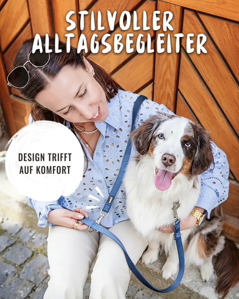 Frau mit Australian Shepherd an einer blauen Hundeleine vor einer Holztür.