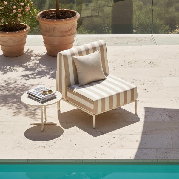 Heller Außenbereich am Pool mit einem gestreiften Loungesessel, einem runden Beistelltisch und zwei großen Pflanzgefäßen aus Terrakotta.