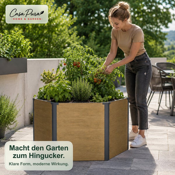 Eine Frau gärtnert an einem hexagonalen Hochbeet in Holzoptik, das mit Kräutern und Tomaten bepflanzt ist, auf einer Terrasse.