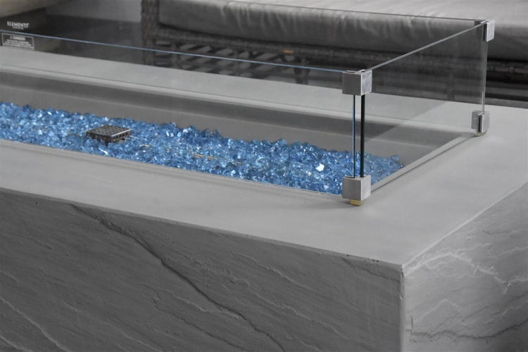 Gaskamin-Tisch aus Beton mit blauen Glassteinen und Windschutz aus Glas.