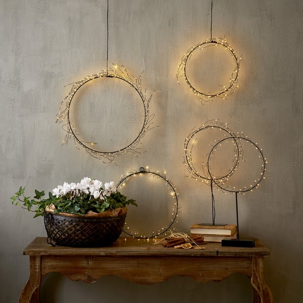 Dekorative Szene mit beleuchteten Kränzen, Blumenschale und rustikalem Holztisch