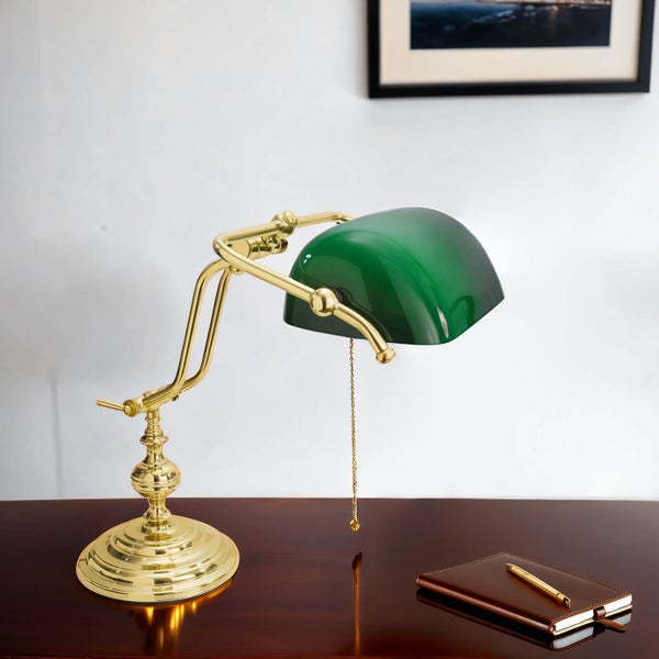 Tischleuchte mit grünem Schirm und goldfarbenem Gestell auf einem Schreibtisch mit Notizbuch und Stift