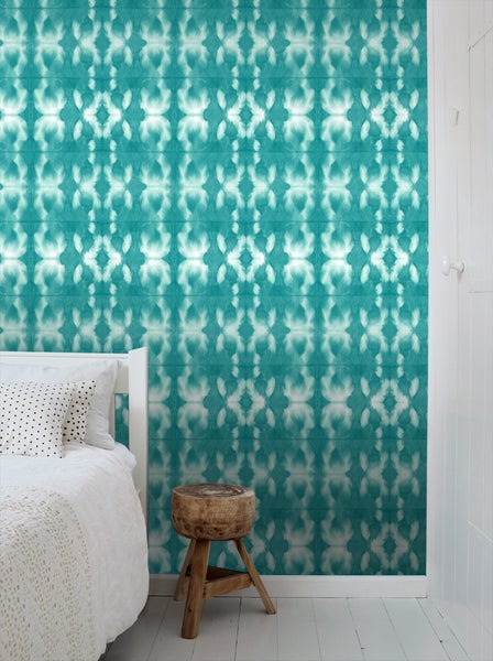 Schlafzimmer mit gemusterter Tapete, Bett und Beistelltisch aus Holz