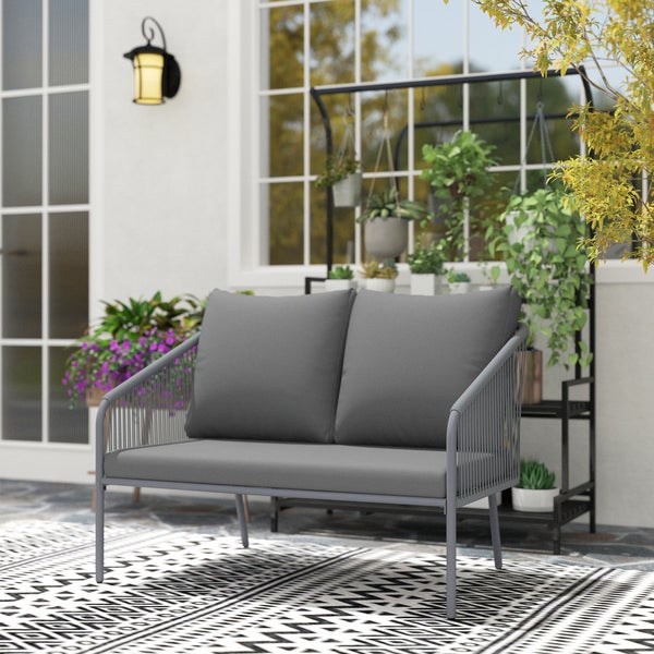 Modernes Zweisitzer Gartensofa mit Metallgestell und grauen Polstern auf einer hellen Terrasse mit Teppich und Pflanzen.
