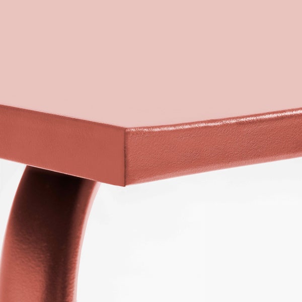 Detailansicht einer Tischkante und eines gebogenen Tischbeins aus pulverbeschichtetem Metall in Rosa.