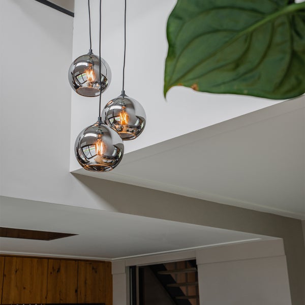 Hängelampe mit drei runden, rauchfarbenen Glasschirmen im Innenraum