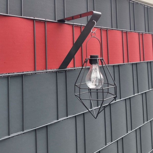 Dekorative Lampe mit Halterung zur Befestigung an einem Zaun.