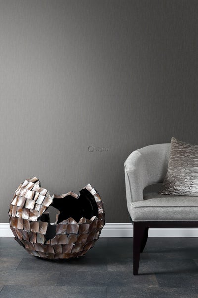 Dekorative Szene mit grauer Tapete, einer Vase aus schimmernden Platten und einem eleganten Sessel.