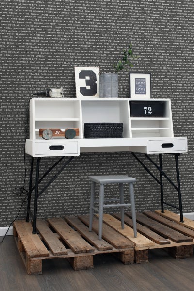 Schreibtisch mit Ablagefächern, Dekoration und Hocker auf einer Europalette vor einer Wand mit Schriftzug
