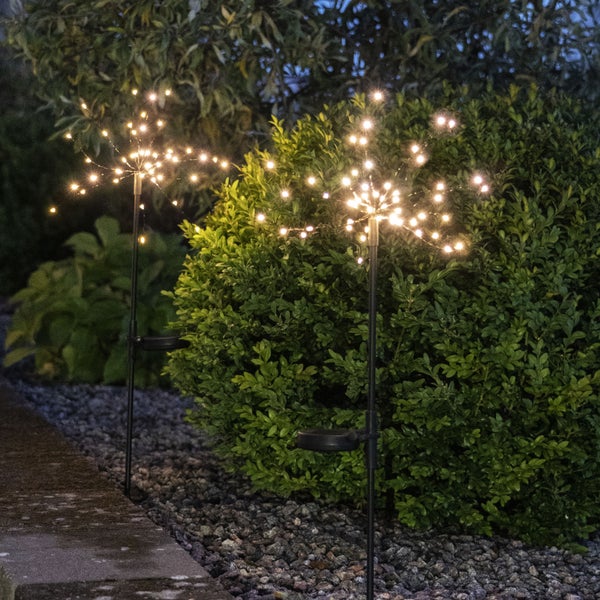 Szene mit einer Stehlampe, zwei Laternen, einer Lichterkette und Pflanzen auf einer Terrasse