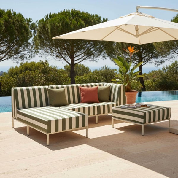 Modernes Garten-Lounge-Set mit gestreiften Polstern, bestehend aus Ecksofa und Hocker auf einer Terrasse am Pool unter einem Sonnenschirm.