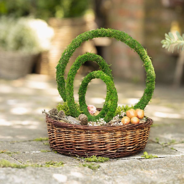 Dekorative Moosringe in geflochtenem Korb mit Blumenschmuck